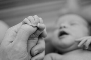 An infant clutching an adult finger.