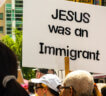 Protesters marching against ICE with a sign that reads "Jesus was an immigrant."