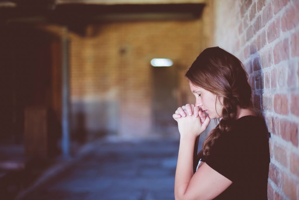 A student is seen praying in the corridor of a building.